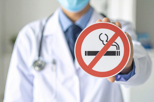 禁煙マークを持つ医師